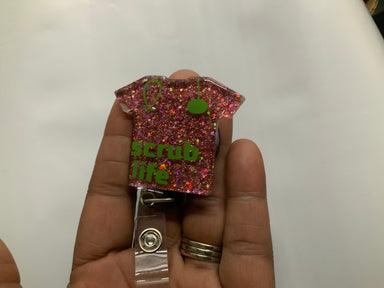 Bling Treasures small scrub top shaped badge reel with the words Scrub Life written on it are fashionable. It comes in variety of colors, red, black, blue, pink, silver & purple.  Length 2 inches width1 1/2 inches Beyond Medwear Apparel
